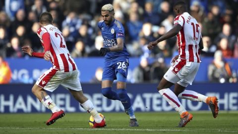 Leicester City's Riyad Mahrez, centre, challenges for the ball with Stoke City's Konstantinos Stafylidis, left, and Bruno Martins Indi during the English Premier League soccer match, Leicester City against Stoke City, at the King Power Stadium, Leicester, England, Saturday Feb. 24, 2018. (Nick Potts/PA via AP)