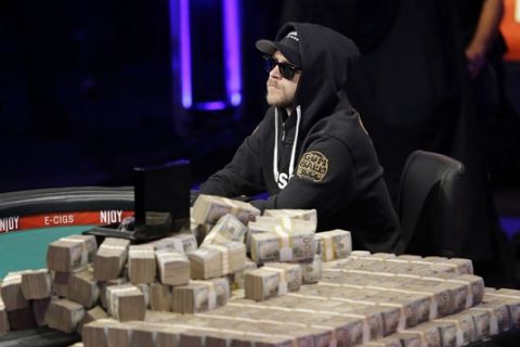 Felix Stephensen plays as a stack of money stands in the foreground during the last night of the World Series of Poker final table Tuesday, Nov. 11, 2014, in Las Vegas. Stephensen and Martin Jacobson were the final two players in the tournament. (AP Photo/John Locher)