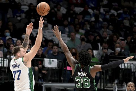 El base de los Mavericks de Dallas Luka Doncic lanza el balón sobre el base de los Celtics de Boston Marcus Smart durante la primera mitad del encuentro del sábado 6 de noviembre del 2021. (AP Photo/Matt Strasen)