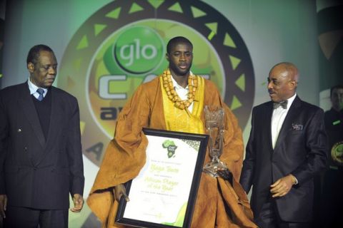 A handout photo provided on December 22, 2011 by the GLO Premier League Ghana Football Association shows Ivory Coast midfielder Yaya Toure (C), who plays for Manchester City, standing on stage with his award and  Globacom human resource executive director Adewale Shangowawa (R) after being named 2011 CAF Footballer of the Year in Accra. Toure, 28, finished ahead of Ghana and Marseille midfielder Andre Ayew and Mali and Barcelona midfielder Seydou Keita in a vote among Africa-based national coaches. Man at left is unidentified.                     AFP PHOTO / GLO / Temmanuel Quaye
RESTRICTED TO EDITORIAL USE - MANDATORY CREDIT "AFP PHOTO / GLO / Temmanuel Quaye" - NO MARKETING NO ADVERTISING CAMPAIGNS - DISTRIBUTED AS A SERVICE TO CLIENTS (Photo credit should read Temmanuel Quaye/AFP/Getty Images)