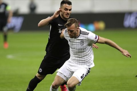 Basel's Silvan Widmer, right, and Frankfurt's Filip Kostic challenge for the ball during a Europa League round of 16, 1st leg soccer match between Eintracht Frankfurt and FC Basel in Frankfurt, Germany, Thursday, March 12, 2020. The match is being played in an empty stadium because of the coronavirus outbreak. (AP Photo/Michael Probst)