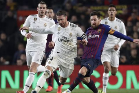Real defender Sergio Ramos, center left, and Barcelona forward Lionel Messi vie for the ball during the Copa del Rey semifinal first leg soccer match between FC Barcelona and Real Madrid at the Camp Nou stadium in Barcelona, Spain, Wednesday Feb. 6, 2019. (AP Photo/Emilio Morenatti)