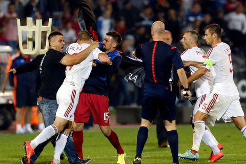 A fight breaks out on the pitch between Serbian fans and Albanian national team players, with from right, Albania's Lorik Cana, Albania's Ansi Agolli, match official, 3rd left Serbia's Nenad Tomovic holding Albanian flag, Albania's Bekim Balaj, and soccer fan at left, during the Euro 2016 Group I qualifying match between Serbia and Albania, at the Partizan stadium in Belgrade, Serbia, Tuesday, Oct. 14, 2014.  The match was suspended on Tuesday after pitch skirmishes involving players and fans over an Albanian flag that was flown above the stadium by a drone.  The score was 0-0 at the time. (AP Photo/Marko Drobnjakovic)