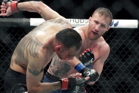 Tony Ferguson, left, falls backward after taking a punch from Justin Gaethje during a UFC 249 mixed martial arts bout, early Sunday, May 10, 2020, in Jacksonville, Fla. (AP Photo/John Raoux)