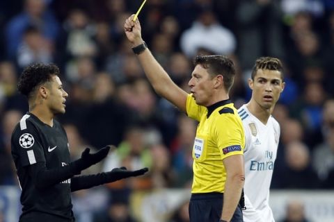 PSG's Neymar, left, reacts after getting a yellow card from referee Gianluca Rocchi of Italy while Real Madrid's Cristiano Ronaldo looks on during a Champions League Round of 16 first leg soccer match between Real Madrid and Paris Saint Germain at the Santiago Bernabeu stadium in Madrid, Spain, Wednesday, Feb. 14, 2018. (AP Photo/Francisco Seco)