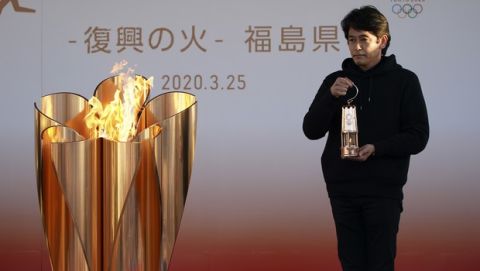 An official holds a lantern containing the Olympic Flame at the end of a flame display ceremony in Iwaki, northern Japan, Wednesday, March 25, 2020. IOC President Thomas Bach has agreed "100%" to a proposal of postponing the Tokyo Olympics for about one year until 2021 because of the coronavirus outbreak. (AP Photo/Eugene Hoshiko)