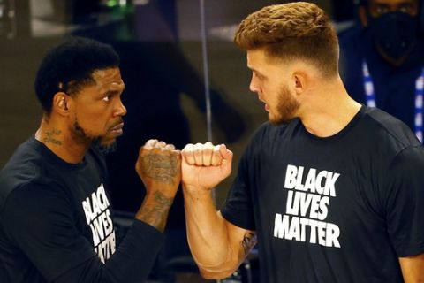 Miami Heat's Meyers Leonard, right, and Udonis Haslem bump fists after Leonard stood during the national anthem before an NBA basketball game against the Denver Nuggets, Saturday, Aug. 1, 2020, in Lake Buena Vista, Fla. (Kevin C. Cox/Pool Photo via AP)