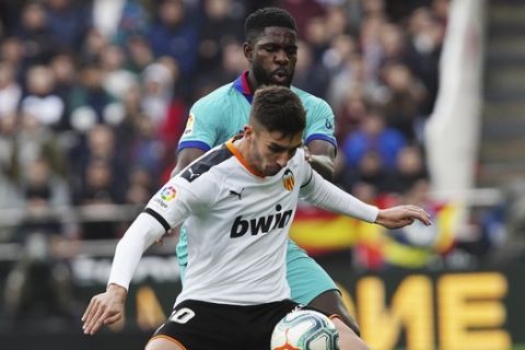 Valencia's Ferran Torres, foreground, challenges for the ball with Barcelona's Samuel Umtiti during the Spanish La Liga soccer match between Valencia and Barcelona at the Mestalla Stadium in Valencia, Spain, Saturday, Jan. 25, 2020. (AP Photo/Alberto Saiz)