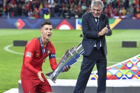 Portugal's Cristiano Ronaldo holds the trophy as he celebrates with his coach Fernando Santos winning the UEFA Nations League final soccer match between Portugal and Netherlands at the Dragao stadium in Porto, Portugal, Sunday, June 9, 2019. Portugal won 1-0. (AP Photo/Martin Meissner)