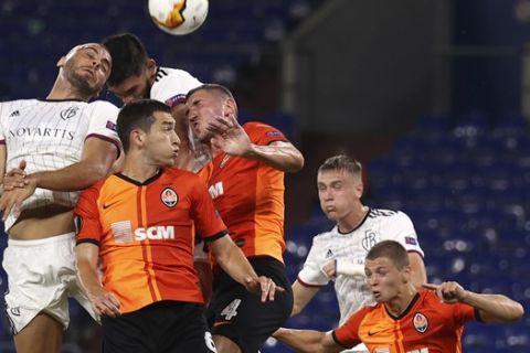 FC Basel's Arthur Cabral, left, Shakhtar's Taras Stepanenko, center, and Shakhtar's Serhiy Kryvtsov jump for the ball during the Europa League quarter-final soccer match between Shakhtar Donetsk and FC Basel at the Veltins-Arena in Gelsenkirchen, Germany, Tuesday, Aug. 11, 2020. (Lars Baron/Pool via AP)