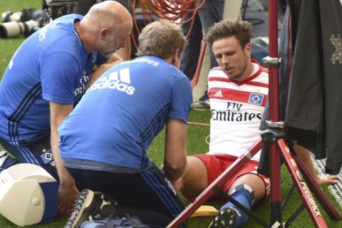 In this Aug. 19, 2017 photo Hamburg's Nicolai Mueller is treated during the German Bundesliga soccer match between Hamburger SV and  FC Augsburg in Hamburg, Germany. Hamburger SV forward Nicolai Mueller is out for around six months after injuring himself while celebrating a goal. The Bundesliga club says Mueller tore a cruciate ligament in his right knee after scoring in Saturday's league-opener, a 1-0 home win over Augsburg. Mueller attempted a pirouette before falling to the ground in apparent pain.  (Daniel Bockwoldt/dpa via AP)