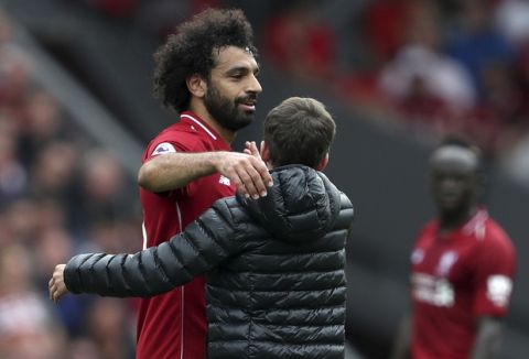 A pitch invader gives Liverpool's Mohamed Salah a hug during the Premier League soccer match between Liverpool and West Ham United at Anfield, Liverpool, England. Sunday August 12, 2018. (David Davies/PA via AP)