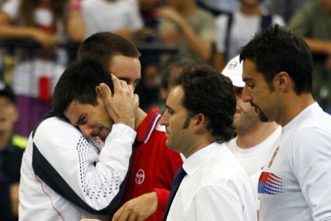 Novak Djokovic (2nd L) of Serbia is comforted by team mates after his Davis Cup World Group semi-final match against Juan Martin Del Potro of Argentina in Belgrade September 18, 2011. Djokovic retired due to injury in the second set. REUTERS/Novak Djurovic (SERBIA - Tags: SPORT TENNIS)