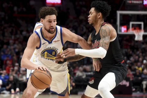 Golden State Warriors guard Klay Thompson, left, dribbles the ball past Portland Trail Blazers guard Anfernee Simons, right, during the second half of an NBA basketball game in Portland, Ore., Sunday, Dec. 17, 2023. The Warriors won 118-114. (AP Photo/Steve Dykes)