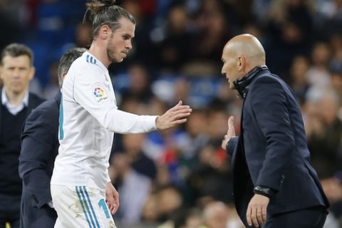 Real Madrid's Gareth Bale. left, shakes hands with Real Madrid's head coach Zinedine Zidane after being substituted during a Spanish La Liga soccer match between Real Madrid and Celta at the Santiago Bernabeu stadium in Madrid, Spain, Saturday, May 12, 2018. (AP Photo/Paul White)