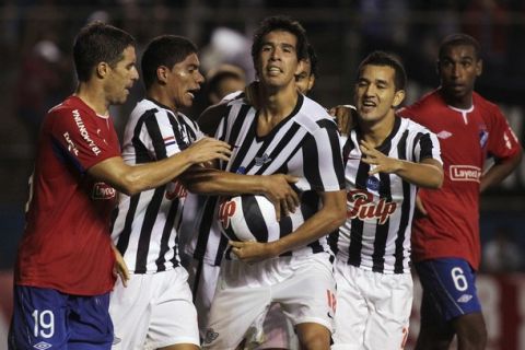 Victor Caceres (C) of Paraguay's Libertad celebrates with teammates after scoring against Uruguay's Nacional Andres Scotti (L) and Alexis Rolin (R) during their Copa Libertadores soccer match in Asuncion April 5, 2012. REUTERS/Jorge Adorno (PARAGUAY - Tags: SPORT SOCCER)