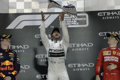 Mercedes driver Lewis Hamilton of Britain, centre, celebrates on the podium after wining the Emirates Formula One Grand Prix as Red Bull driver Max Verstappen of the Netherland's, left, and Ferrari driver Charles Leclerc of Monaco, look on at the Yas Marina racetrack in Abu Dhabi, United Arab Emirates, Sunday, Dec.1, 2019. (AP Photo/Luca Bruno)