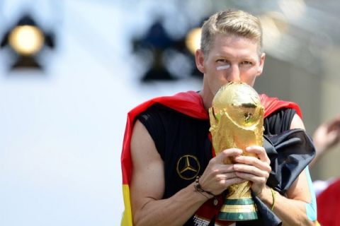 TO GO WITH AFP STORY by DANIEL ARONSSOHN - FILES - Germany's national football team's midfielder Bastian Schweinsteiger kisses the trophy as he celebrates their FIFA World Cup 2014 title at a victory parade in front of fans on July 15, 2014 at Berlin's landmark Brandenburg Gate. German midfield general Bastian Schweinsteiger is favourite to become the World Cup winners' captain after the surprise international retirement of Philipp Lahm. AFP PHOTO / ROBERT MICHAELROBERT MICHAEL, ROBERT MLCHAEL/AFP/Getty Images ORG XMIT: 2496 ORIG FILE ID: 531764986
