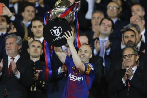 FC Barcelona's Andres Iniesta holds up the trophy as he celebrates during an award ceremony after defeating Sevilla 5-0 in the Copa del Rey final soccer match at the at the Wanda Metropolitano stadium in Madrid, Spain, Saturday, April 21, 2018. (AP Photo/Francisco Seco)