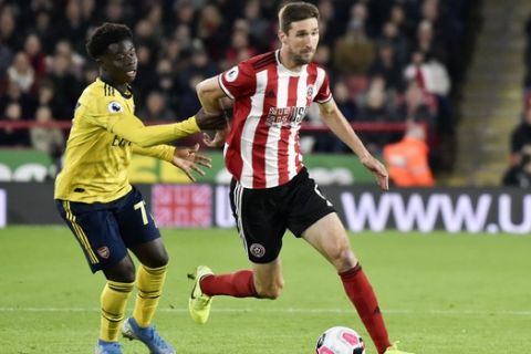 Sheffield United's Chris Basham, right, and Arsenal's Bukayo Saka challenge for the ball during the English Premier League soccer match between Sheffield United and Arsenal at Bramall Lane in Sheffield, England, Monday, Oct. 21, 2019. (AP Photo/Rui Vieira)