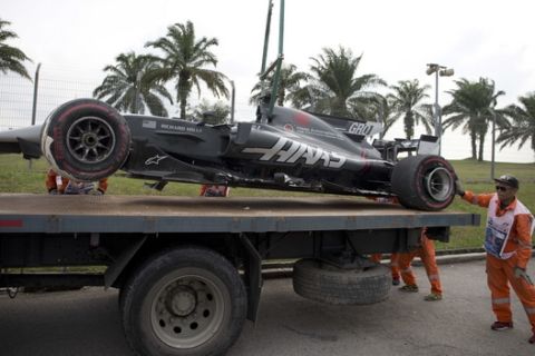 Track crew lifting Haas driver Romain Grosjean of France car after it crashed out on Turn 14 during the second practice at the Sepang International Circuit for the first practice session for the Malaysian Formula One Grand Prix in Sepang, Malaysia, Friday, Sept. 29, 2017. (AP Photo/Thomas Lam)