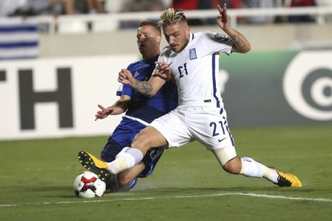 Cyprus' Jason Demetriou, left, challenges for the ball with Greece' s Kostas Stafylidis during their World Cup Group H qualifying soccer match between Cyprus and Greece at GSP stadium in Nicosia, Cyprus, Saturday, Oct. 7, 2017. (AP Photo/Petros Karadjias)
