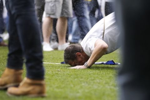 A fan kisses the grass as the pitch is invaded after the English Premier League soccer match between Tottenham Hotspur and Manchester United at White Hart Lane stadium in London, Sunday, May 14, 2017. It was the last Spurs match at the old stadium, a new stadium is being built on the site. (AP Photo/Frank Augstein)