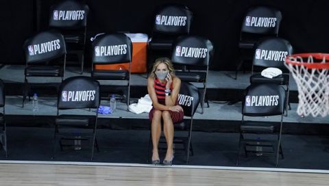 A reporter sits beside an empty court after a postponed NBA basketball first round playoff game between the Milwaukee Bucks and the Orlando Magic, Wednesday, Aug. 26, 2020, in Lake Buena Vista, Fla. The game was postponed after the Milwaukee Bucks didn't take the floor in protest against racial injustice and the shooting of Jacob Blake, a Black man, by police in Kenosha, Wisconsin. (AP Photo/Ashley Landis, Pool)