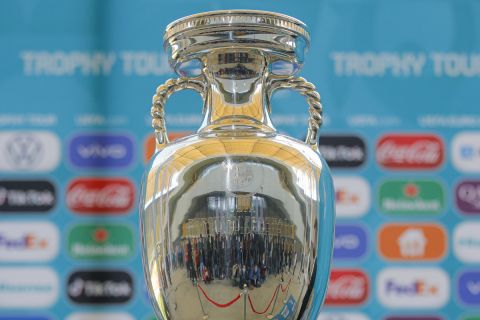 Journalists are reflected in the Euro 2020 soccer tournament trophy at the National Arena stadium, a tournament venue, in Bucharest, Romania, Sunday, April 25, 2021. The trophy of the tournament was presented outside some Romanian capital landmarks, like the communist era built House of the People, currently housing the country's parliament, during an event that ended at the National Arena stadium. (AP Photo/Vadim Ghirda)