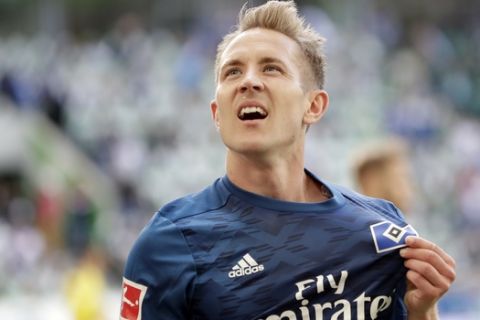 Hamburg's scorer Lewis Holtby displays his team's logo as he celebrates after scoring his side's 2nd goal during the German Bundesliga soccer match between VfL Wolfsburg and Hamburger SV in Wolfsburg, Germany, Saturday, April 28, 2018. (AP Photo/Michael Sohn)