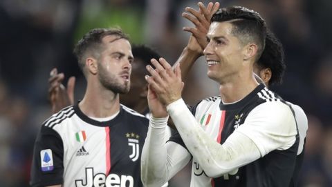 Juventus' Cristiano Ronaldo and his teammate Miralem Pjanic celebrates at the end of a Serie A soccer match between Juventus and Bologna, at the Allianz stadium in Turin, Italy, Saturday, Oct.19, 2019. Juventus won 2-1. (AP Photo/Luca Bruno)