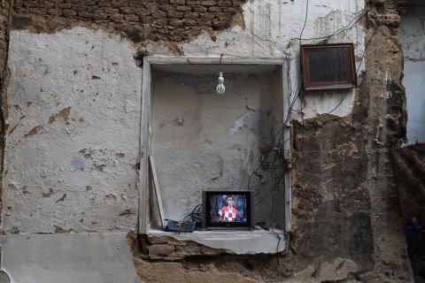 Syrians watch Croatia's Mario Mandzukic on a small television during the World Cup soccer final match between France and Croatia at their home, that was partially destroyed by the war leaving two of its rooms without a ceiling, in the town of Ain Terma, in the Eastern Ghouta suburb of Damascus, Syria, Sunday, July 15, 2018. (AP Photo/Hassan Ammar)