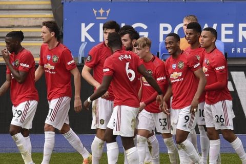 Manchester United's Bruno Fernandes celebrates with teammates after scoring his side's opening goal from the penalty spot during the English Premier League soccer match between Leicester City and Manchester United at the King Power Stadium, in Leicester, England, Sunday, July 26, 2020. (Oli Scarff/Pool via AP)