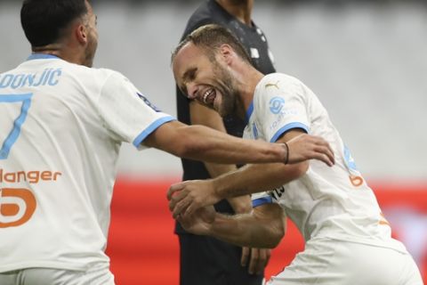 Marseille's Valere Germain, right, is congratulated by teammate Nemanja Radonjic, right, after scoring his team's first goal during the French League One soccer match between Marseille and Lille at the Stade Velodrome in Marseille, France, Sunday Sept. 20, 2020. (AP Photo/Daniel Cole)