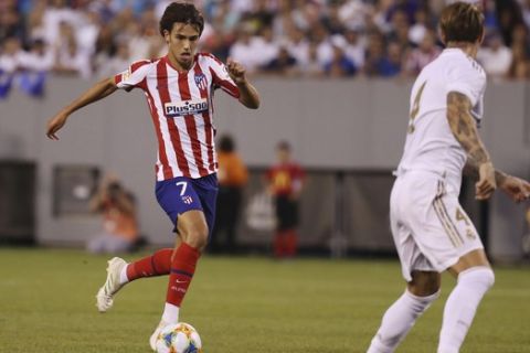 Atletico Madrid forward Joao Felix, left, moves the ball towards goal while Real Madrid defender Sergio Ramos looks to defend during the first half of an International Champions Cup soccer match, Friday, July 26, 2019, in East Rutherford, N.J. Atletico Madrid won 7-3. (AP Photo/Steve Luciano)