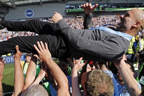 Manchester City coach Pep Guardiola is lifted in the air by the players after the English Premier League soccer match between Brighton and Manchester City at the AMEX Stadium in Brighton, England, Sunday, May 12, 2019. Manchester City defeated Brighton 4-1 to win the championship. (AP Photo/Frank Augstein)