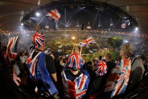 Spectators, dressed in the colors of the flag of Great Britain, wave the national flag during the Opening Ceremony at the 2012 Summer Olympics, Saturday, July 28, 2012, in London. (AP Photo/Markus Schreiber)