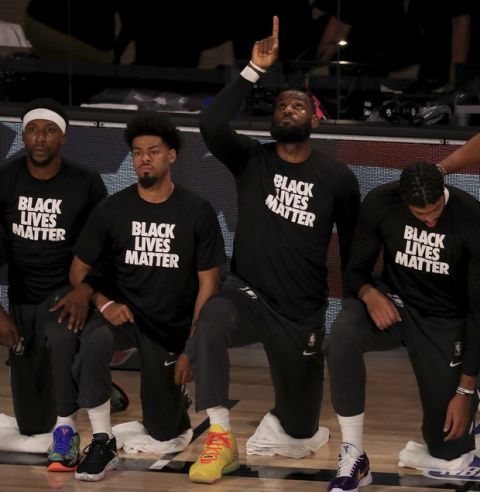 Los Angeles Lakers' LeBron James wears a Black Lives Matter shirt as he points up and kneels with teammates during the national anthem prior to an NBA basketball game against the Los Angeles Clippers, Thursday, July 30, 2020, in Lake Buena Vista, Fla. (Mike Ehrmann/Pool Photo via AP)