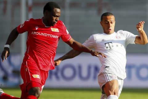 FC Union Berlin's Anthony Ujah in action with Bayern Munich's Thiago, right, during the German Bundesliga soccer match between Union Berlin and Bayern Munich in Berlin, Germany, Sunday, May 17, 2020. The German Bundesliga becomes the world's first major soccer league to resume after a two-month suspension because of the coronavirus pandemic. (AP Photo/Hannibal Hanschke, Pool)