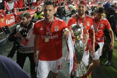Benfica's Andreas Samaris, center and team captain Jardel carry the trophy around the stadium close to the fans after the Portuguese league last round soccer match between Benfica and Santa Clara at the Luz stadium in Lisbon, Saturday, May 18, 2019. Benfica won 4-1 to clinch the championship title. (AP Photo/Armando Franca)