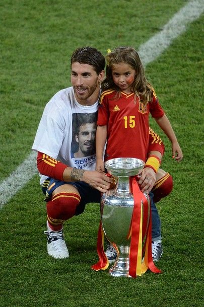 Spanish defender Sergio Ramos pose with the trophy and a young girl during the Euro 2012 football championships final match Spain vs Italy on July 1, 2012 at the Olympic Stadium in Kiev. Spain won 4-0. AFP PHOTO / JEFF PACHOUD        (Photo credit should read JEFF PACHOUD/AFP/GettyImages)