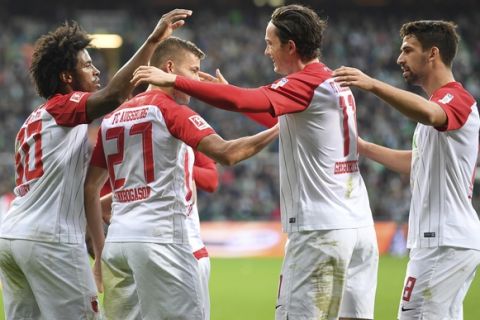 Augsburg's Caiuby, left, Alfred Finnbogason, second left, and Rani Khedira, right, celebrate the opening goal by Michael Gregoritsch, second right, during the German Bundesliga soccer match between SV Werder Bremen and FC Augsburg  in Bremen, Germany, Sunday, Oct. 29, 2017.  (Carmen Jaspersen/dpa via AP)
