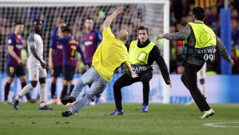 Stewards stop a fan who ran onto the pitch during the Champions League semifinal first leg soccer match between FC Barcelona and Liverpool at the Camp Nou stadium in Barcelona, Spain, Wednesday, May 1, 2019. (AP Photo/Manu Fernandez)