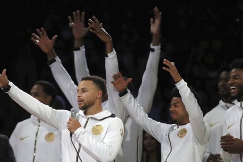 Golden State Warriors' Stephen Curry, left, speaks to fans during an awards ceremony to recognize the team's NBA championship prior to a basketball game against the Oklahoma City Thunder, Tuesday, Oct. 16, 2018, in Oakland, Calif. (AP Photo/Ben Margot)