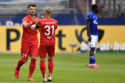 Augsburg's Eduard Loewen, left, celebrates with Augsburg's Philipp Max after scoring his side's opening goal during the German Bundesliga soccer match between FC Schalke 04 and FC Augsburg at the Veltins-Arena in Gelsenkirchen, Germany, Sunday, May 24, 2020. The German Bundesliga becomes the world's first major soccer league to resume after a two-month suspension because of the coronavirus pandemic. (AP Photo/Martin Meissner, Pool)