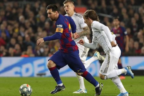 Barcelona's Lionel Messi, left, vies for the ball with Real Madrid's Luka Modric, right, during a Spanish La Liga soccer match between Barcelona and Real Madrid at Camp Nou stadium in Barcelona, Spain, Wednesday, Dec. 18, 2019. Thousands of Catalan separatists are planning to protest around and inside Barcelona's Camp Nou Stadium during Wednesday's "Clasico". (AP Photo/Emilio Morenatti)