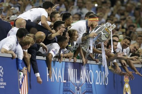 Real Madrid's Sergio Ramos holds the trophy as he celebrates with teammates winning the Champions League final soccer match between Real Madrid and Atletico Madrid at the San Siro stadium in Milan, Italy, Saturday, May 28, 2016. Real Madrid won 5-4 on penalties after the match ended 1-1 after extra time. (AP Photo/Andrew Medichini)