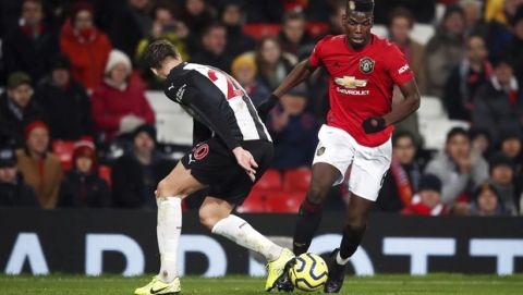 Manchester United's Paul Pogba, right, and Newcastle United's Florian Lejeune battle for the ball during their English Premier League soccer match at Old Trafford, Manchester, England, Thursday, Dec. 26, 2019. (Martin Rickett/PA via AP)