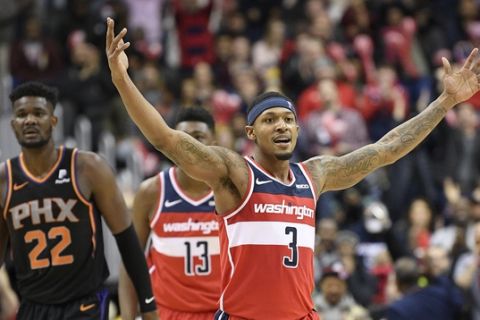 Washington Wizards guard Bradley Beal (3) gestures in front of Phoenix Suns center Deandre Ayton (22) during the second half of an NBA basketball game, Saturday, Dec. 22, 2018, in Washington. Wizards center Thomas Bryant (13) looks on. (AP Photo/Nick Wass)