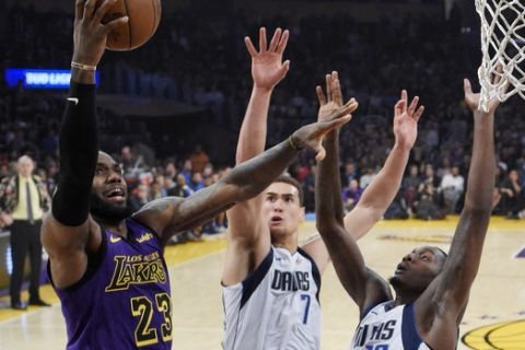 Los Angeles Lakers forward LeBron James, left, shoots as Dallas Mavericks forward Dwight Powell, center, and forward Dorian Finney-Smith defend during the first half of an NBA basketball game Friday, Nov. 30, 2018, in Los Angeles. (AP Photo/Mark J. Terrill)
